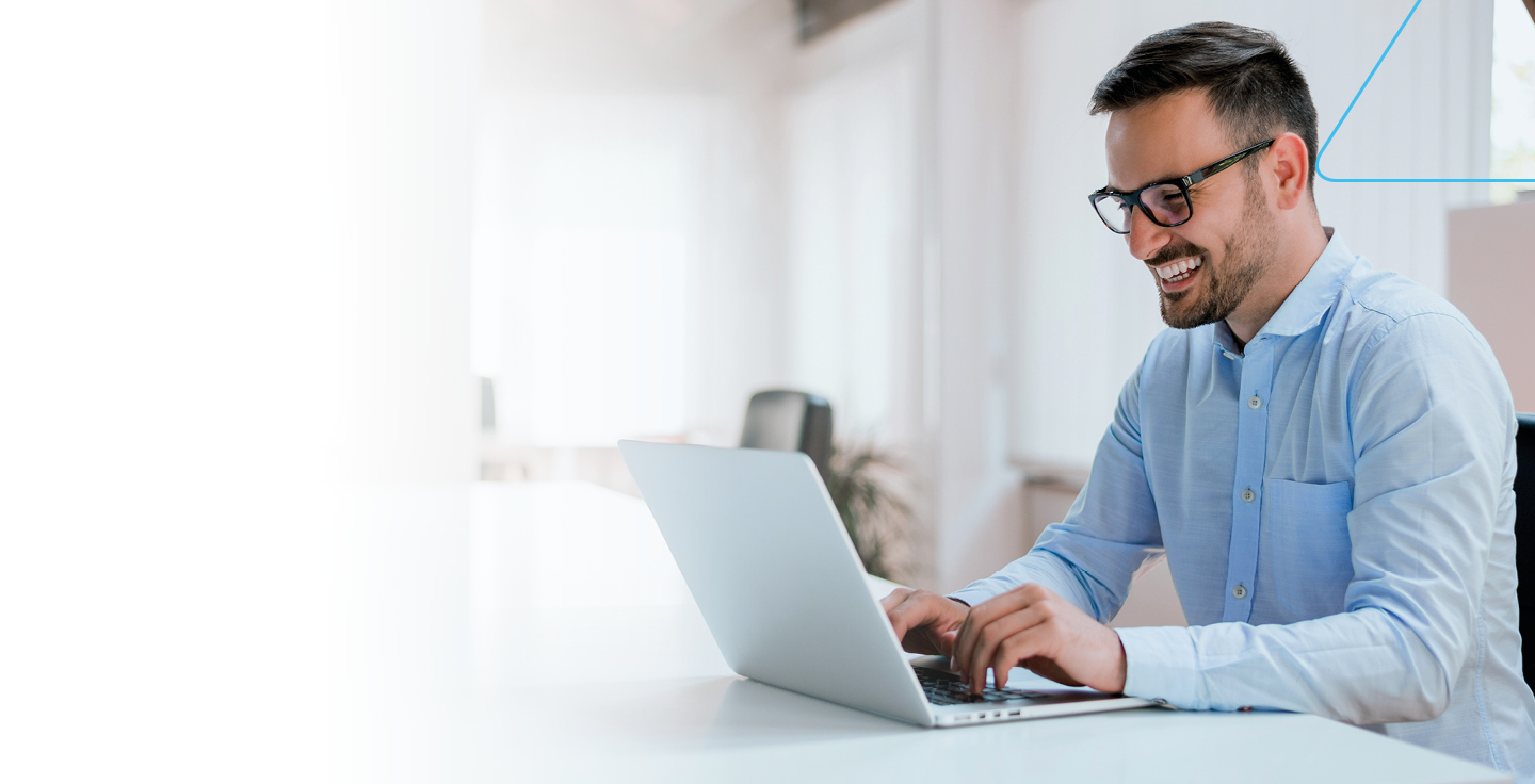 Foto de homem em frente a um notebook sorrindo